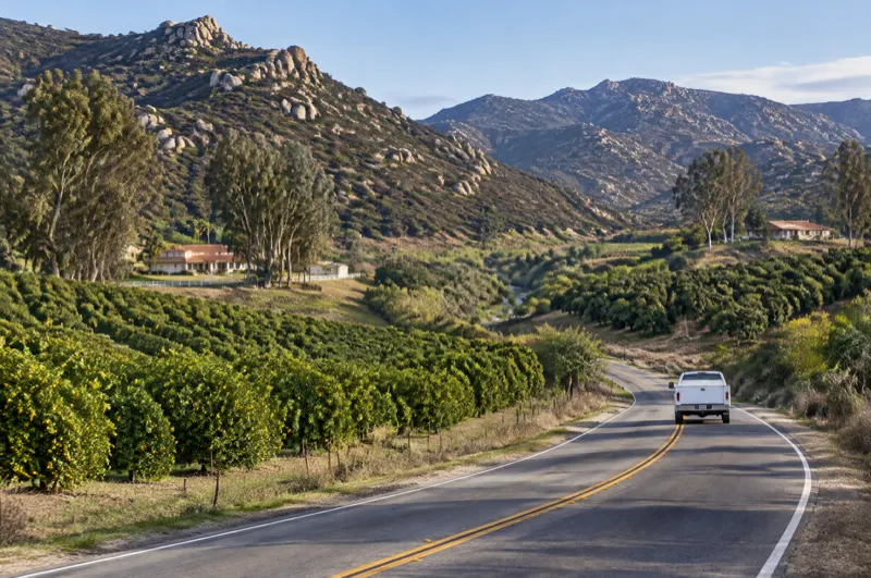 Two-lane highway through citrus groves and granite hills in the San Luis Rey River valley